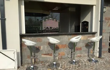 Quincho con barra y taburetes para compartir la previa del asado